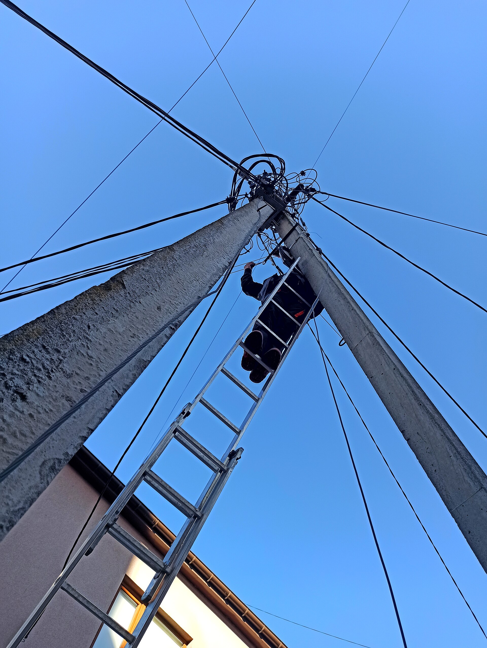 A technician working on fiber optic network equipment on a utility pole
